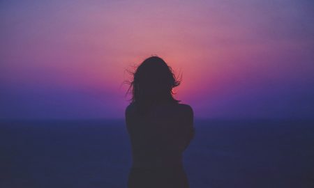 Weekly Horoscope - Silhouette of a woman with pink and purple sky.